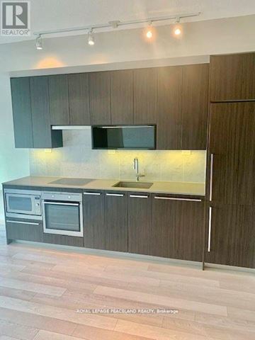 Toronto (Bayview Village) condo for rent - A modern kitchen with dark wood cabinets and stainless steel appliances.