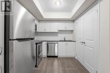 Toronto (Eglinton East) townhouse for rent - A modern kitchen with white cabinets and stainless steel appliances.