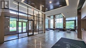 Markham (Unionville) condo for rent - A spacious lobby with a glass wall and a bench.