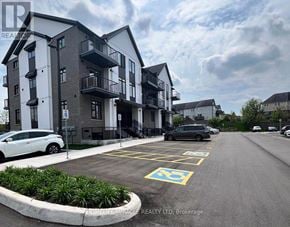 Cambridge townhouse for rent - A parking lot with a white car and a black car parked in front of a building.