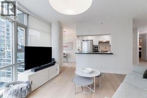 Vancouver apartment for rent - A modern living room with a flat screen TV and a kitchen area in the background.