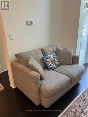Toronto (Willowdale East) condo for rent - A beige couch with a blue pillow is in the foreground of a room.