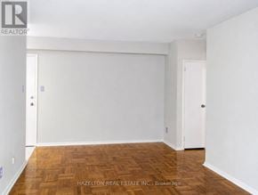 Toronto (Annex) condo for rent - A room with wooden flooring and white walls, with a door on the left and another on the right.