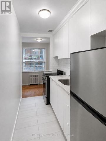Toronto (Annex) condo for rent - A modern kitchen with white cabinets and a stainless steel refrigerator.
