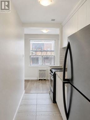 Toronto (Annex) condo for rent - A kitchen with a refrigerator, oven, and a window with a view of a balcony.