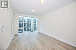 Grimsby condo for rent - A spacious room with wooden flooring and a large window overlooking a cityscape.