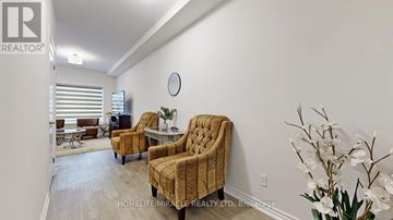 Niagara Falls (Hospital) townhouse for rent - A living room with a yellow patterned chair and a white vase with white flowers.