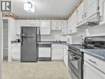 Windsor condo for rent - A kitchen with white cabinets and appliances.