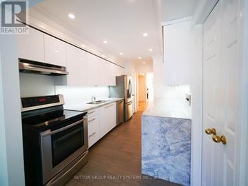 Toronto (Kensington-Chinatown) townhouse for rent - A modern kitchen with white cabinets and a stainless steel oven.