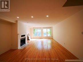 Toronto (Kensington-Chinatown) townhouse for rent - A spacious room with a fireplace and wooden floors.