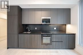 Toronto (Waterfront Communities) condo for rent - A modern kitchen with dark wood cabinets and a black countertop.