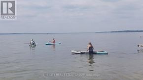 Georgina (Keswick South) apartment for rent - A woman is standing on a paddleboard in the middle of a body of water.