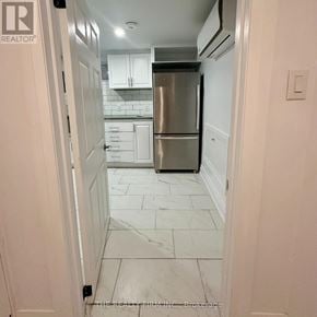 Toronto (Rockcliffe-Smythe) duplex for rent - A kitchen with a refrigerator, cabinets, and a marble floor.