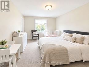 Russell townhouse for rent - A bedroom with a large bed, a chair, a nightstand, and a window.