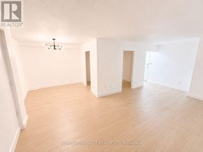 Toronto (Flemingdon Park) condo for rent - A spacious room with wooden flooring and white walls.