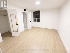 Toronto (Flemingdon Park) condo for rent - A room with wooden flooring and white walls, with a door and a window.