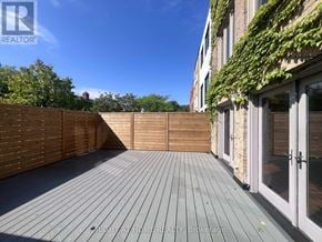 Toronto (Yonge-St. Clair) apartment for rent - A wooden deck with a fence and a building with glass doors in the background.