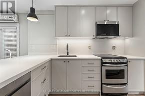 Toronto (The Beaches) duplex for rent - A modern kitchen with white cabinets and a stainless steel oven.