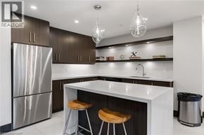 Burlington condo for rent - A modern kitchen with a stainless steel refrigerator, bar stools, and a white countertop.