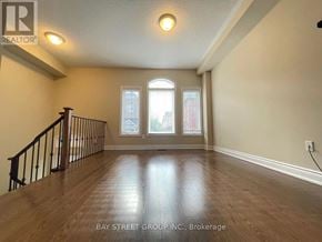 Richmond Hill (Westbrook) townhouse for rent - A spacious room with wooden flooring and a staircase leading to the upper level.