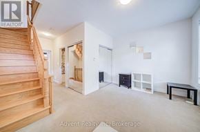 Markham (Commerce Valley) townhouse for rent - A spacious room with a staircase, a black dresser, a white shelf, and a black table.