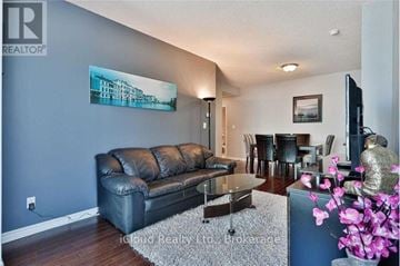 Mississauga (Hurontario) condo for rent - A living room with a black leather couch and a painting on the wall.