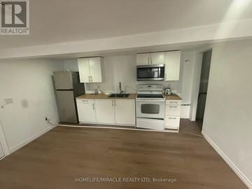Woodstock (Woodstock - North) apartment for rent - A kitchen with white cabinets and appliances in a room with wooden flooring.