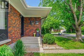 Ottawa apartment for rent - A house with a brick facade and a black door is surrounded by greenery.