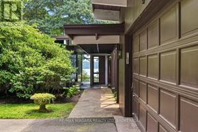 St. Catharines (Martindale Pond) apartment for rent - A house entrance with a garage door and a bushy green lawn.
