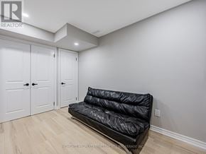 Ajax (Northeast Ajax) townhouse for rent - A black sofa in a room with white walls and wooden flooring.