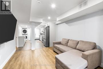 Ajax (Northeast Ajax) apartment for rent - A living room with a couch and a kitchen area in the background.