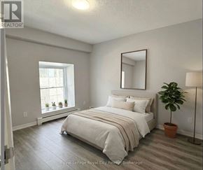 Guelph (Downtown) multi-family for rent - A bedroom with a bed, a mirror, and a potted plant.