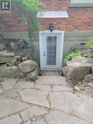 Caledon (Bolton West) apartment for rent - A small white door with a window is surrounded by rocks and plants.