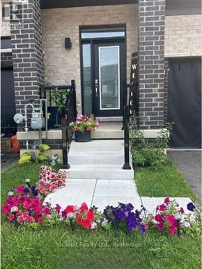 Brantford townhouse for rent - A front yard with a black door and a flower bed with purple and pink flowers.