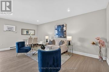 St. Catharines (Secord Woods) multi-family for rent - A living room with a blue chair and a glass table with a vase of flowers on it.