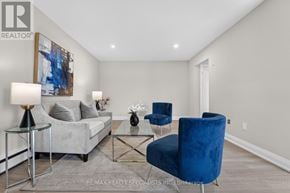 St. Catharines (Secord Woods) multi-family for rent - A living room with a grey couch, a blue chair, and a glass coffee table.