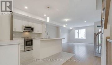 Ottawa townhouse for rent - A spacious kitchen with white cabinets and a microwave above the oven.