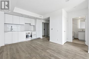 Toronto (Leaside) condo for rent - A spacious kitchen with white cabinets and a wooden floor.