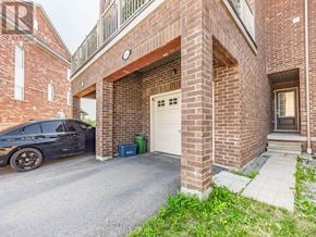 Ajax (Northeast Ajax) townhouse for rent - A black car is parked in front of a brick building with a white garage door.