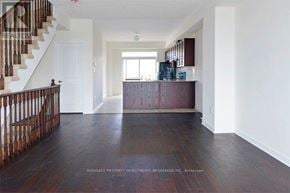 Ajax (Northeast Ajax) townhouse for rent - A spacious room with wooden floors and a staircase on the left side.