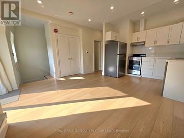 Toronto (Little Portugal) multi-family for rent - A kitchen with white cabinets and a wooden floor.