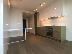 Surrey apartment for rent - A modern kitchen with a wooden floor and white cabinets.