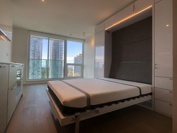 Surrey apartment for rent - A bedroom with a large bed and a kitchen area.