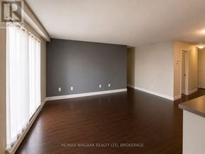 St. Catharines (Downtown) multi-family for rent - A spacious room with wooden floors and white walls.