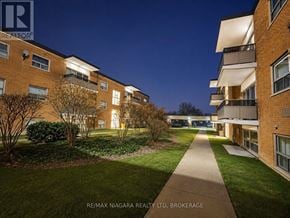 St. Catharines (Oakdale) condo for rent - A residential building complex at night with a pathway leading to the entrance.