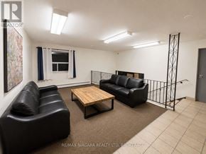 St. Catharines (Oakdale) condo for rent - A living room with black leather furniture and a wooden coffee table.
