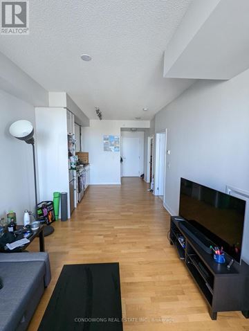 Toronto (Waterfront Communities) condo for rent - A living room with a grey sofa and a black television.