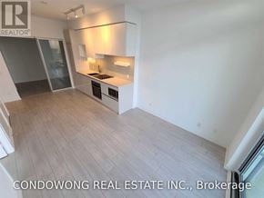 Vaughan (Vaughan Corporate Centre) condo for rent - A modern kitchen with white cabinets and a wooden floor.