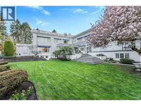Vancouver apartment for rent - A white building with a green lawn in front and a tree with pink flowers to the right.