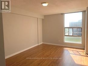 Brampton (Queen Street Corridor) condo for rent - A room with wooden flooring and a window showing a view of a building.